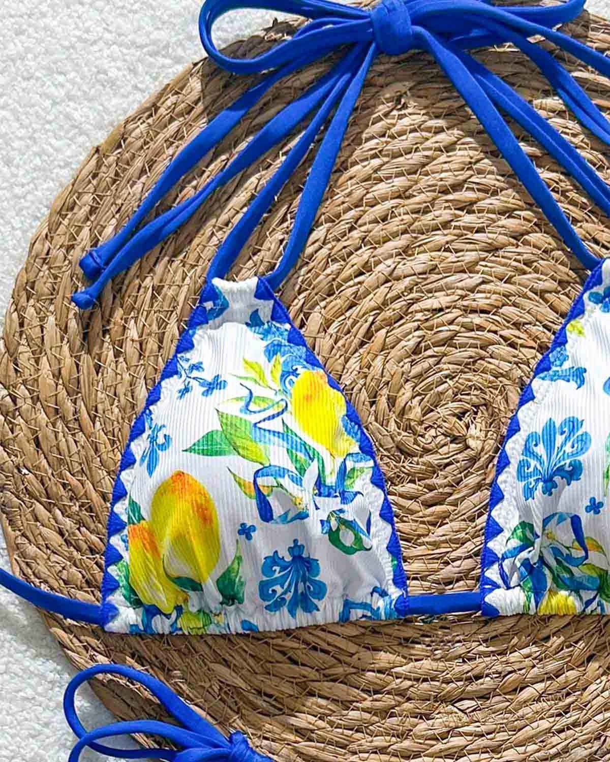 Bikini top with floral design and blue straps on a woven mat